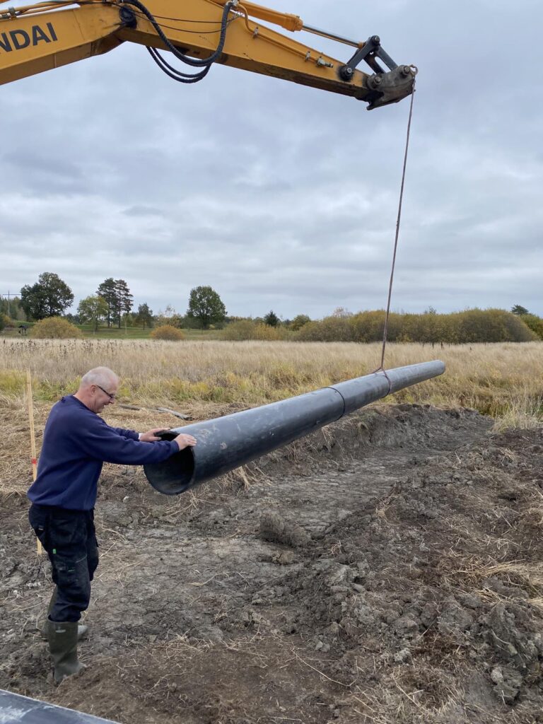 Ned läggning av rören som ska leda vatten in och ut från våtmarken. 8/10 2024